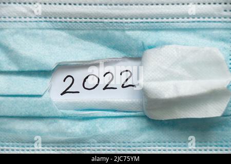 2022 écrit sur papier sur un masque médical déchiré, bonne année 2022, soins de santé, vacances et médecine Banque D'Images