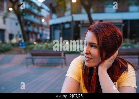 une jeune fille assise sur la terrasse d'un bar de la ville discutant avec ses amis le soir. femme profitant de son temps libre. concept de vie nocturne Banque D'Images