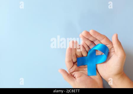 Vue de dessus du ruban de sensibilisation bleu des mains. Cancer de la prostate, cancer du côlon et cancer colorectal, concept de soins de la paix, de l'alopécie et de l'arthrite. Banque D'Images