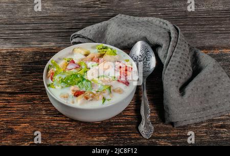 Soupe froide russe traditionnelle okroshka avec pommes de terre fraîches, concombre, tomate, œufs durs et kéfir. Pose plate, fond en bois Banque D'Images