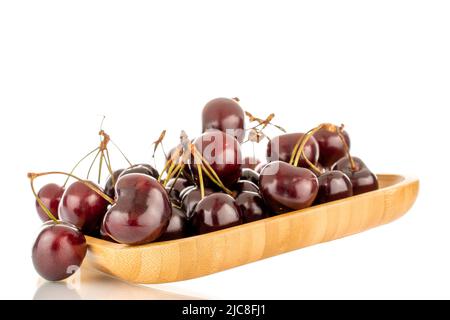 Plusieurs cerises douces sur une plaque de bambou, en gros plan, isolées sur un fond blanc. Banque D'Images