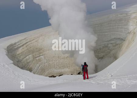 Un skieur regardant la vapeur s'échapper d'un évent sur un volcan Banque D'Images