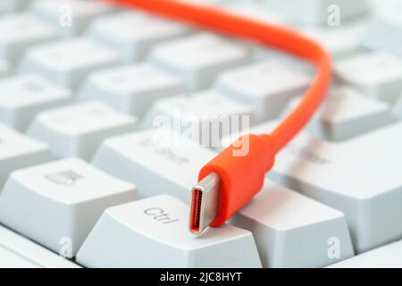 Le câble orange avec le connecteur de type c se trouve sur le clavier blanc. Foyer sélectif, DOF peu profond. Banque D'Images