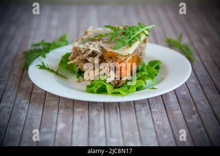 viande en gelée avec légumes verts et légumes dans une assiette sur une table en bois Banque D'Images