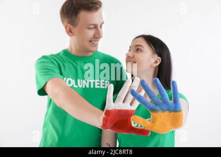 Volontaires aux mains peintes en couleurs de drapeaux ukrainiens et polonais sur fond blanc Banque D'Images