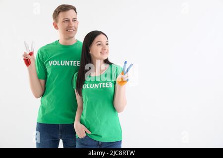 Volontaires aux mains peintes en couleurs de drapeaux ukrainiens et polonais montrant un geste de victoire sur fond blanc Banque D'Images