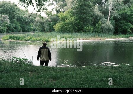 Silhouette d'un pêcheur, d'une canne et d'une scène à couper le souffle dans la forêt avec des reflets colorés sur la rivière. Article sur la chasse de jour de pêche pour Banque D'Images