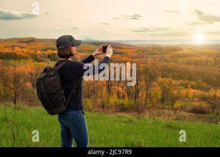 Le modèle féminin d'âge moyen fait du selfie sur un smartphone en montagne Banque D'Images