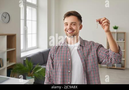 Portrait d'un jeune homme heureux souriant et montrant les clés de sa maison nouvellement achetée Banque D'Images