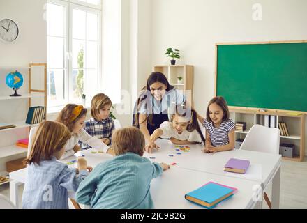 Les enseignantes et les élèves du secondaire junior ont du plaisir à mettre ensemble des puzzles en classe. Banque D'Images