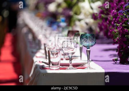 Décoration table de fête avec fleurs violettes et blanches et verrerie sur nappe. Mise au point sélective Banque D'Images