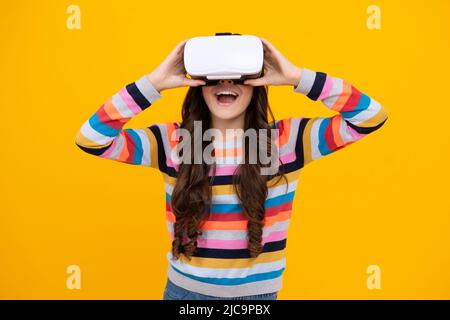 Adolescent stupéfié. Gadgets virtuels pour les enfants, temps libre et étude. Une adolescente utilise des lunettes vr, isolées sur fond jaune. Jeune fille excitée. Banque D'Images