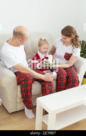 Enfant fille vêtue d'une robe de noël avec implants cochléaires s'amusant à la maison - diversité et aide auditive et technologies innovantes pour le traitement Banque D'Images