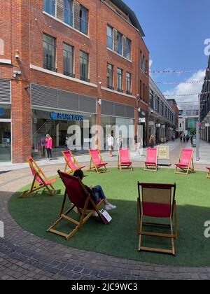 Newbury, berkshire, Angleterre, Royaume-Uni. 2022. Chaises longues sur l'herbe à utiliser par les acheteurs dans le centre-ville. Banque D'Images