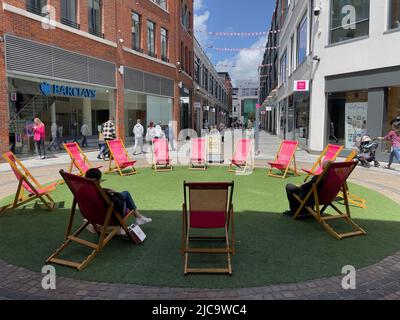 Newbury, berkshire, Angleterre, Royaume-Uni. 2022. Chaises longues sur l'herbe à utiliser par les acheteurs dans le centre-ville. Banque D'Images