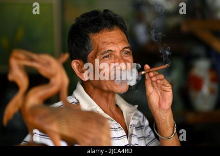 Jakarta, Indonésie. Joyeux homme content fumant un cigare de cheroot dans un magasin de commerce de rue. PHOTO DE SAM BAGNALL Banque D'Images