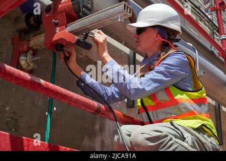 Un ouvrier de construction de base fore dans un mur de soutènement en béton Banque D'Images