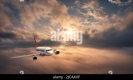 L'avion vole au-dessus des nuages au coucher du soleil en été Banque D'Images