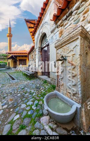 Ancienne fontaine du temple soufi avec le minaret de la mosquée Tekke de Halveti en arrière-plan, Prizren, Kosovo Banque D'Images