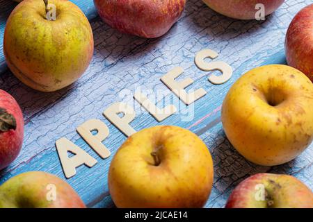 Beaucoup de pommes jaunes et rouges fruit avec des pommes mot écrit sur des lettres en bois sur un fond bleu Banque D'Images