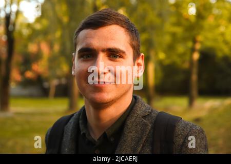 Flou artistique portrait jeune homme sur fond nature automne. Jeune homme souriant. 20s ans. Bel homme en plein air portrait. Marche dans le parc. Style de vie. Goujon Banque D'Images
