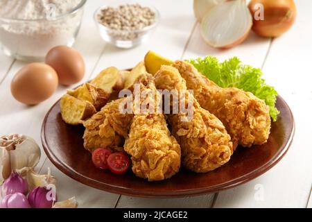une assiette de poulet frits et croustillant servie avec des quartiers de pommes de terre, des légumes et certains ingrédients Banque D'Images
