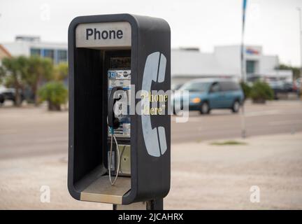 Public Pay Phone, à pièces, à côté d'une rue animée est un ancien et sale type analogique, mais toujours en état de marche comme la circulation conduit par dans backgro Banque D'Images