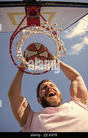 homme joueur réussi lancer ballon de basket-ball à travers le panier, succès Banque D'Images