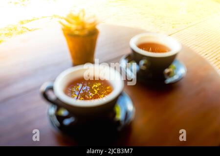 Mise au point douce et éclairage doux sur deux tasses à thé noir et soucoupes sur une table en bois à l'extérieur. Tisane en Asie. Banque D'Images