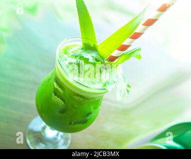 Boisson tropicale verte glacée servie à la plage au Vietnam. A une paille striée rouge dans un grand verre transparent. Banque D'Images