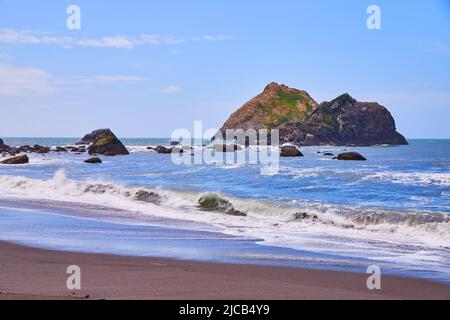 De grandes rochers dans l'océan avec plage de sable et vagues s'écrasant Banque D'Images