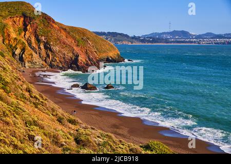 Les vagues de l'océan s'écrasant sur les plages de sable de la côte ouest à côté des collines Banque D'Images