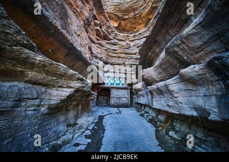 Couches de falaises à travers le canyon avec chemin pavé menant à l'entrée de la grotte Banque D'Images