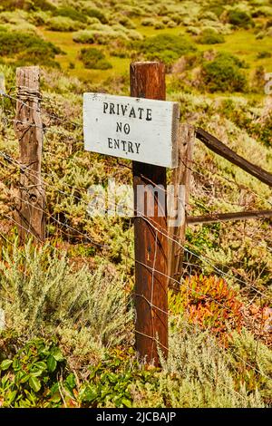 Panneau privé d'interdiction d'entrée sur la clôture métallique près du champ de printemps Banque D'Images