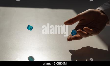 Femme lance une paire de dés bleus transparents. Banque D'Images