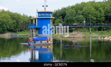 Brebes, Indonésie - 12 décembre 2021 : tour de contrôle du niveau d'eau dans le réservoir de Malahayu avec fond forestier et bateaux de pêche autour. Banque D'Images