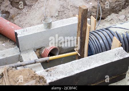 tuyaux ondulés pour câbles électriques et un poste de pilotage en béton dans l'excavation en construction de routes Banque D'Images