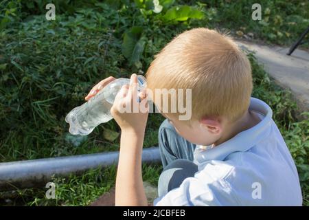 enfant d'une bouteille pour verser de l'eau sur la tête de l'été Banque D'Images