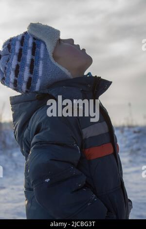 En hiver, le garçon regarda le ciel et regarde de près Banque D'Images