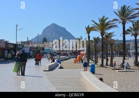 Javea, Alicante, Espagne - 11 mai 2022: La plage Arenal avec des touristes, des magasins et des restaurants sur le front de mer et la montagne Montgo en arrière-plan Banque D'Images