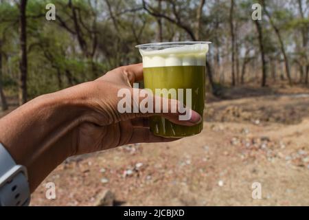 Personne tenant et buvant un verre de jus de canne à sucre frais et bio provenant d'un local alimentaire de rue dans la zone rurale du village en été temps chaud à quench Banque D'Images