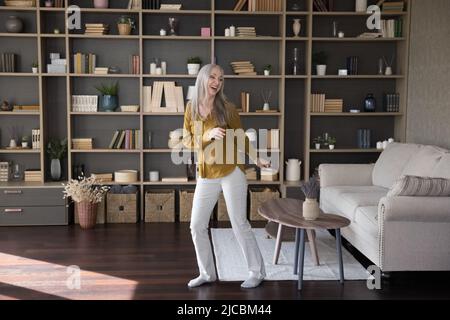 Une femme active d'âge moyen danse dans un salon moderne Banque D'Images