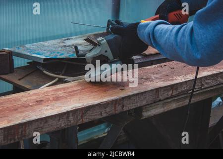 un homme meule une planche. Élimination de l'ancienne peinture des panneaux. Travail de menuiserie. Concentration sélective Banque D'Images