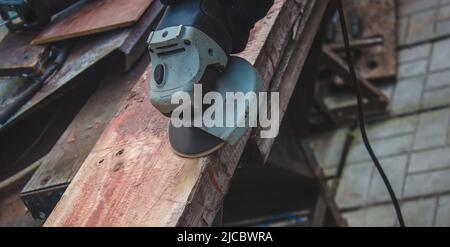 un homme meule une planche. Élimination de l'ancienne peinture des panneaux. Travail de menuiserie. Concentration sélective Banque D'Images