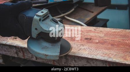 un homme meule une planche. Élimination de l'ancienne peinture des panneaux. Travail de menuiserie. Concentration sélective Banque D'Images