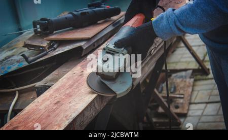 un homme meule une planche. Élimination de l'ancienne peinture des panneaux. Travail de menuiserie. Concentration sélective Banque D'Images