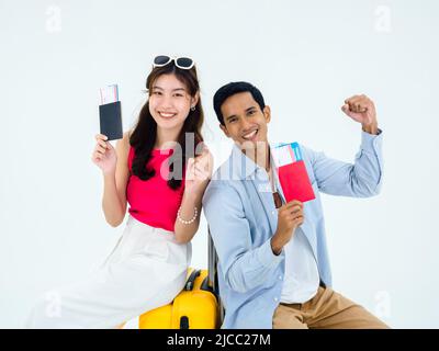 Prêt à voyager, joyeuses vacances. Concept de vacances d'été. Un couple asiatique souriant tenant le poing levé, montrant passeport avec succès, jeune femme et homme Banque D'Images