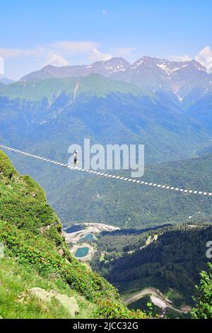 Un homme marche sur un pont suspendu dans les montagnes Banque D'Images