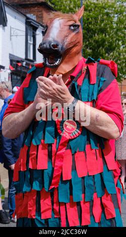 Le danseur de Merrydowers Morris, dans un pelage de pâte et une tête de cheval, se serre les mains sur Pinner High Street à la St George's Day Celebration 2022. Nord-Ouest de Londres. Banque D'Images