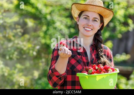 portrait en gros plan d'une jeune femme paysanne souriante avec des fraises dans un bol Banque D'Images